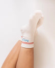 White knee-high sock with red and blue stripes on a person's leg against a white background